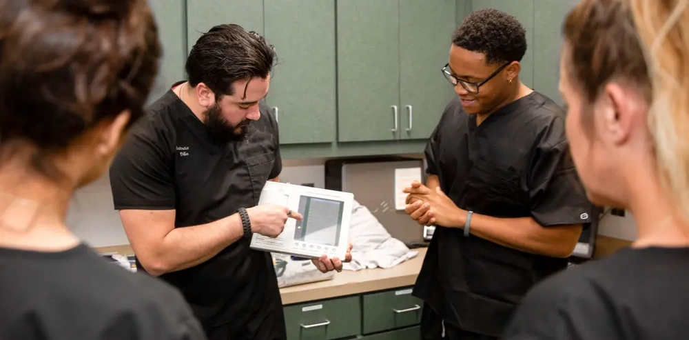 students observing their instructor demonstrating how to use dental equipment